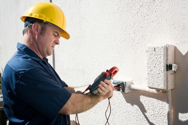 Male Electrician Working On Fusebox With Screwdriver